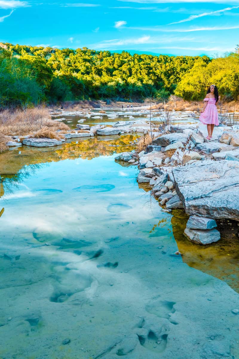 Woman in a pink dress standing by a serene blue river