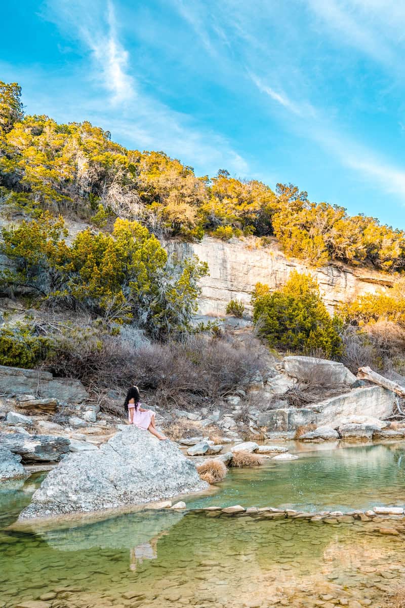 Person sitting on a rock by a serene river