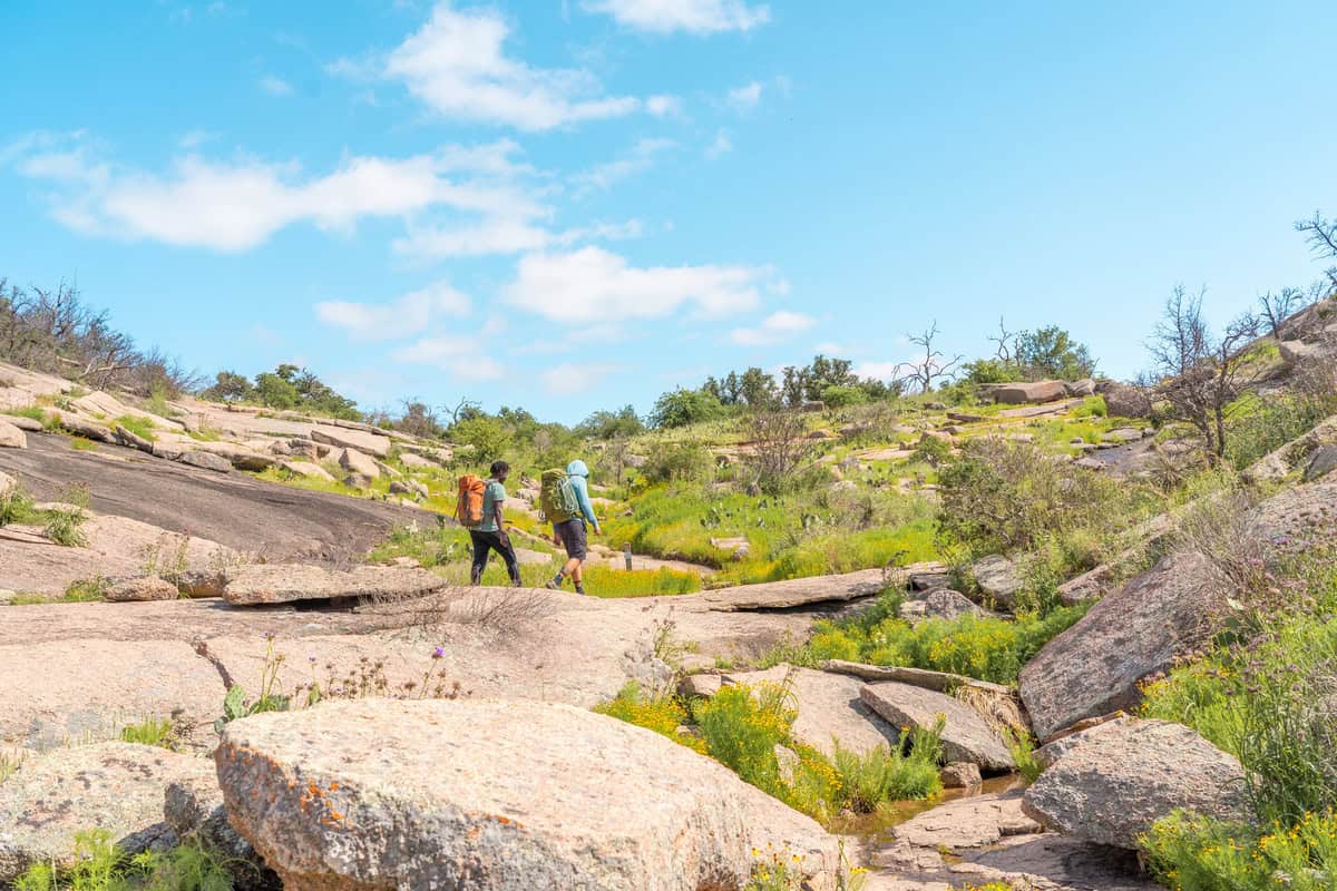 Two hikers with backpacks walking on rocky terrain