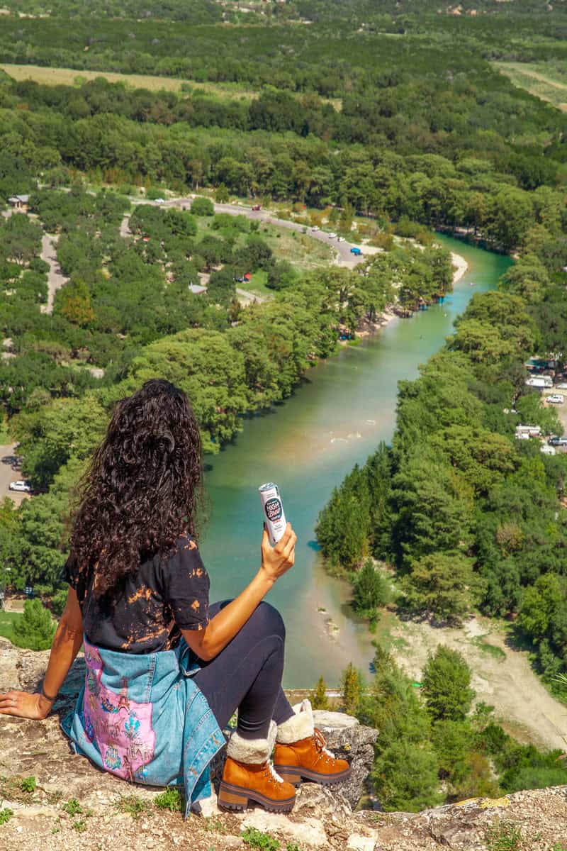 Woman sitting on a cliff overlooking a winding river