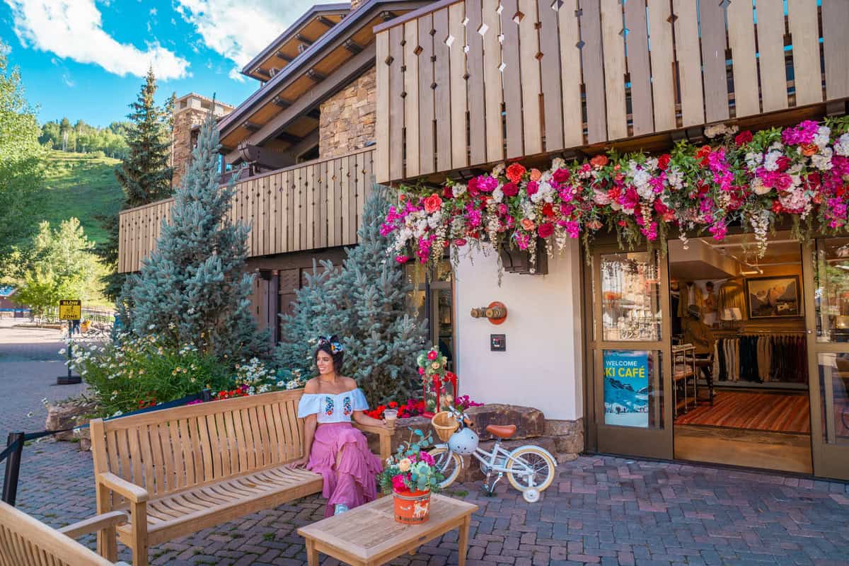 Person sitting on a bench outside a flower-adorned cafe