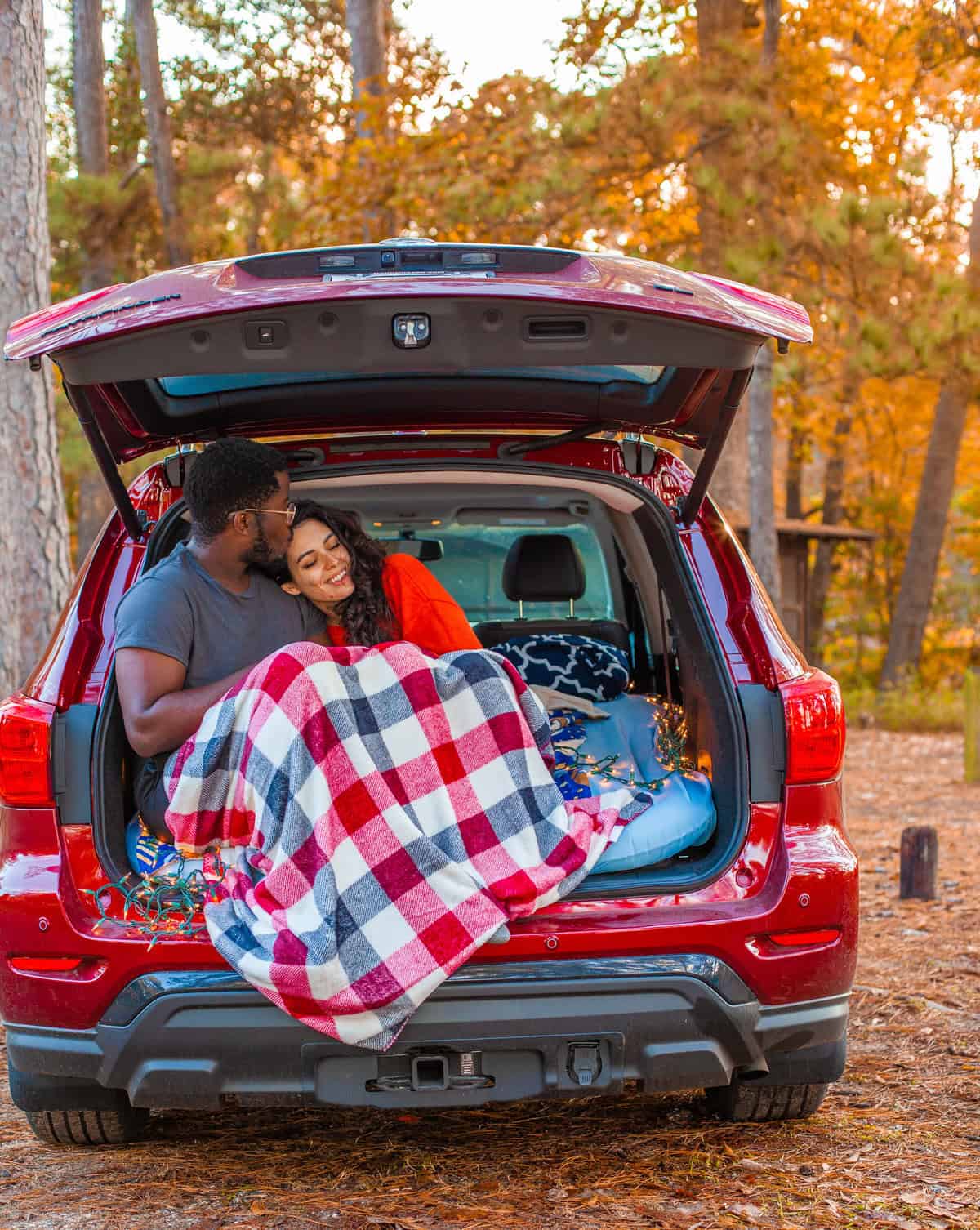 Two people under a blanket in the trunk