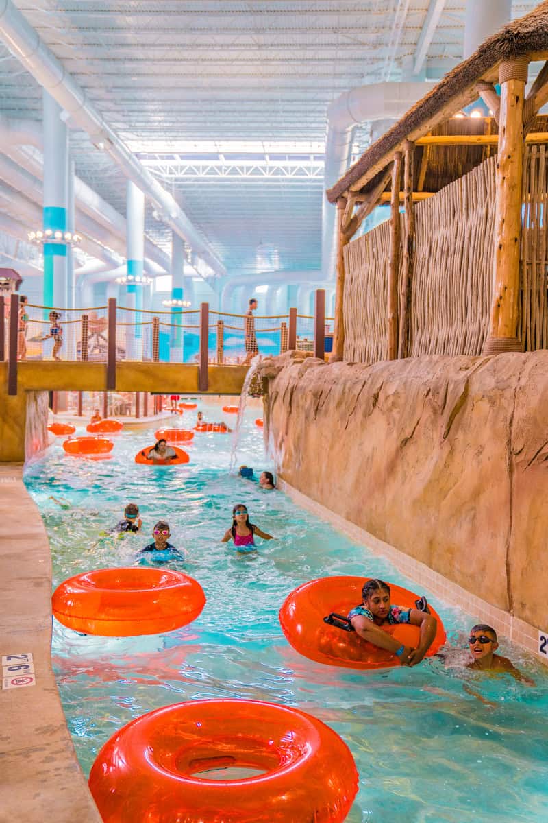 People floating on orange tubes in an indoor lazy river