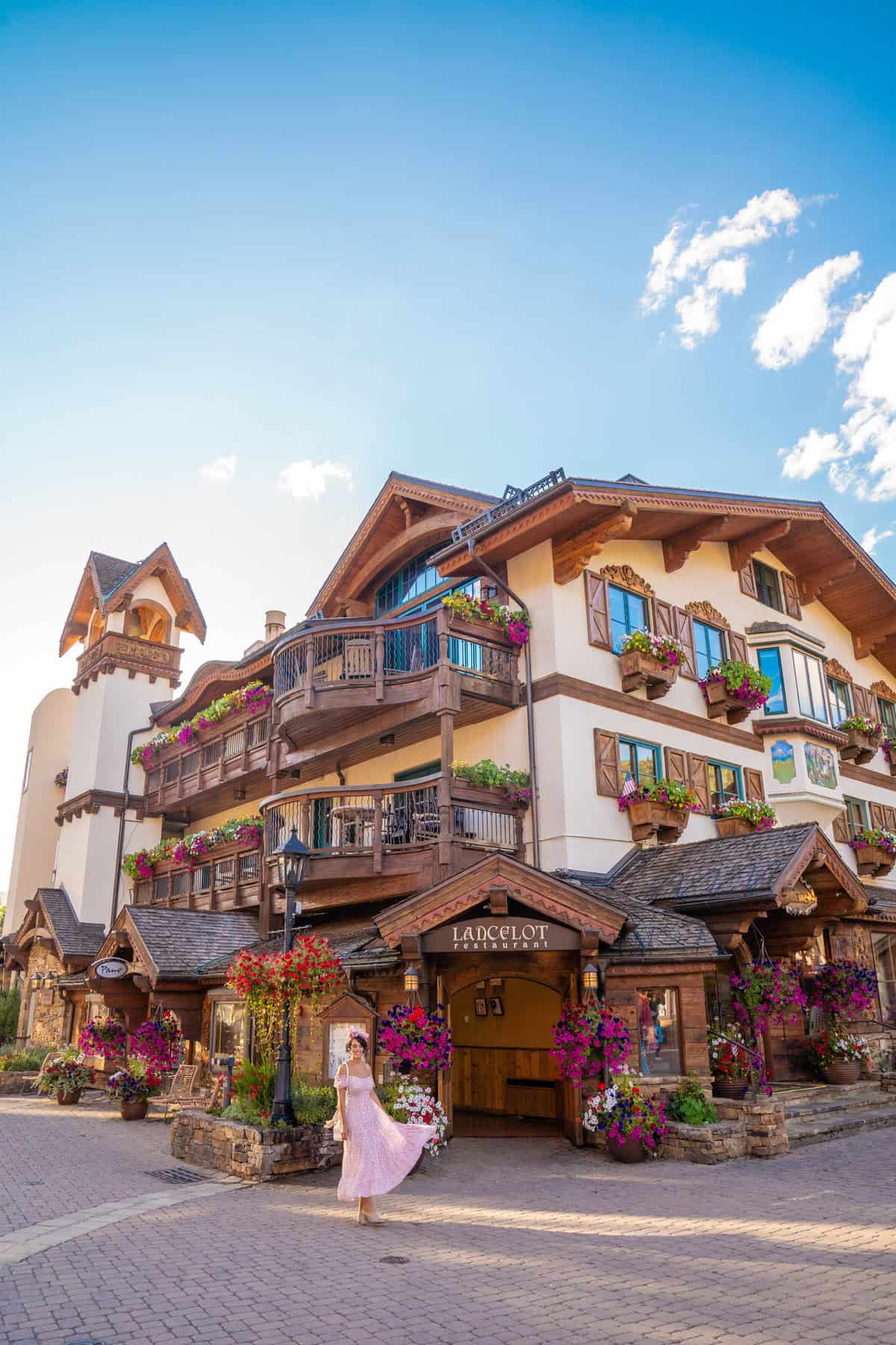 A person in a pink dress outside a charming alpine-style building