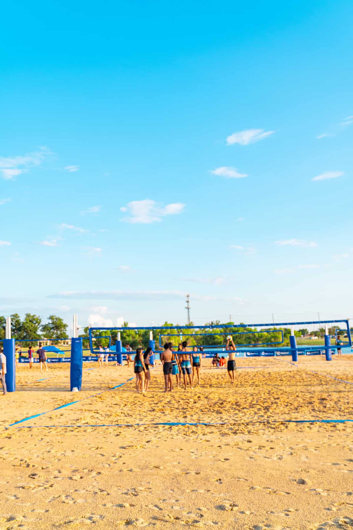 People playing beach volleyball under a clear blue sky.