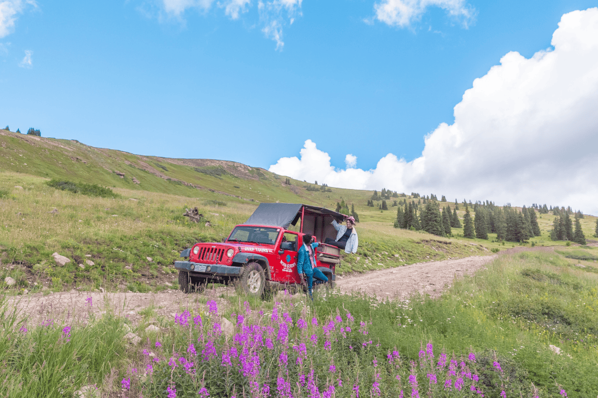 Red jeep with open hatch and two people