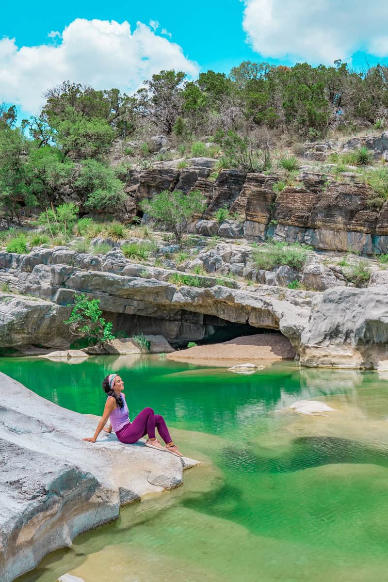 Person sitting by a green water pool