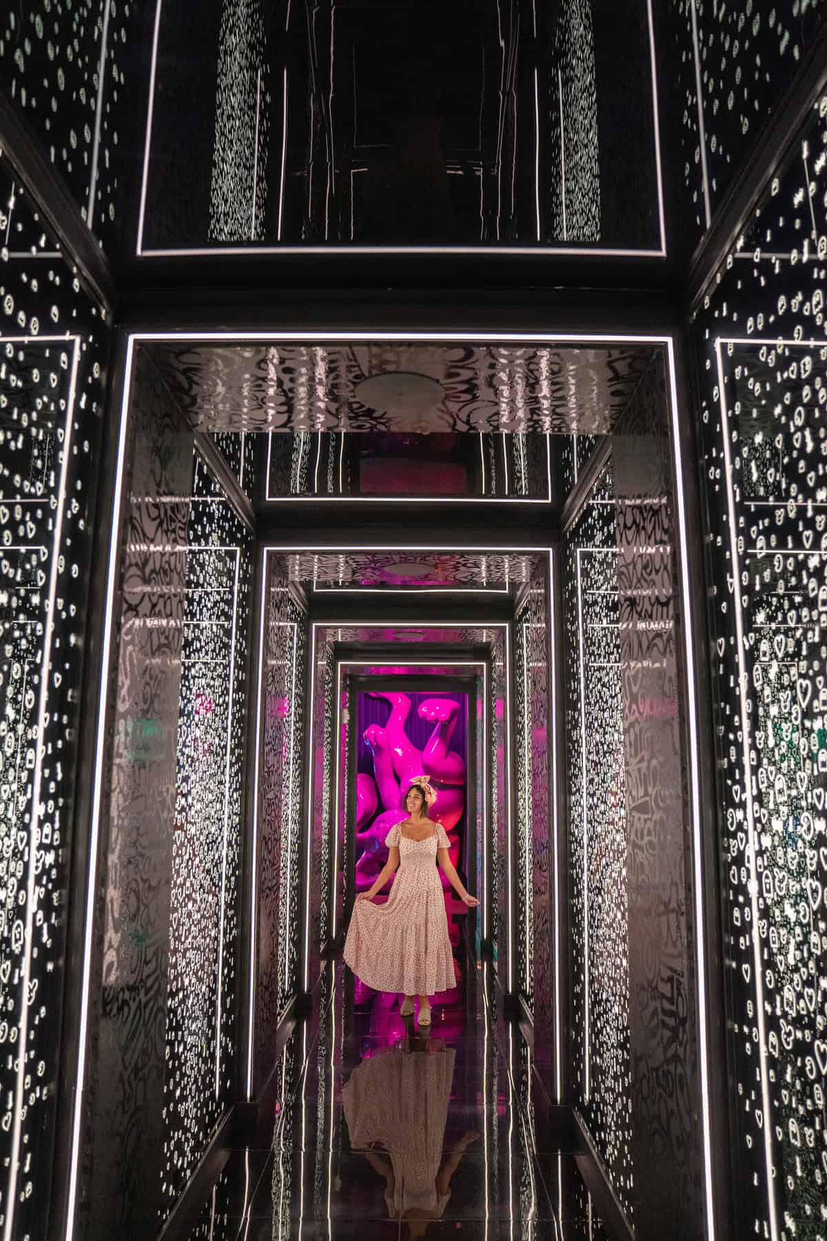 A person in a dress walking through a mirrored hallway