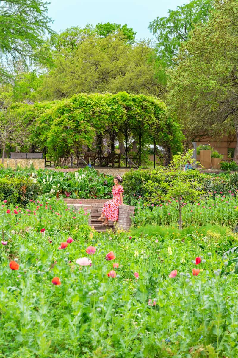 A woman enjoying a peaceful moment, enveloped by the beauty of a blooming garden.