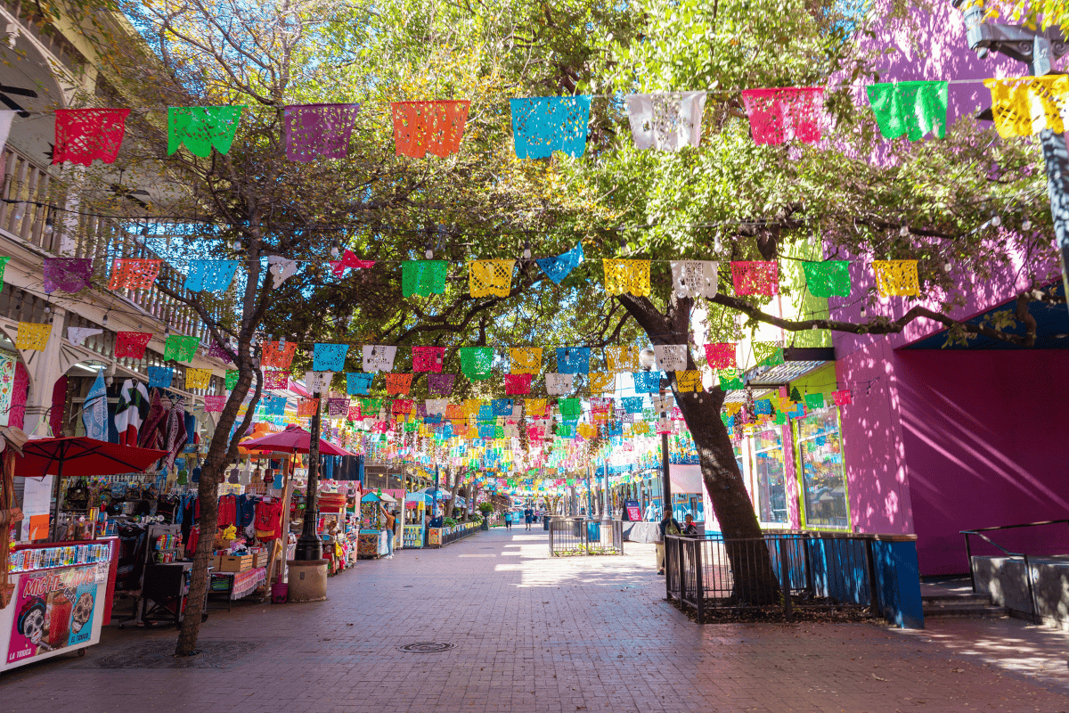 A vibrant street adorned with colorful banners hanging from trees,