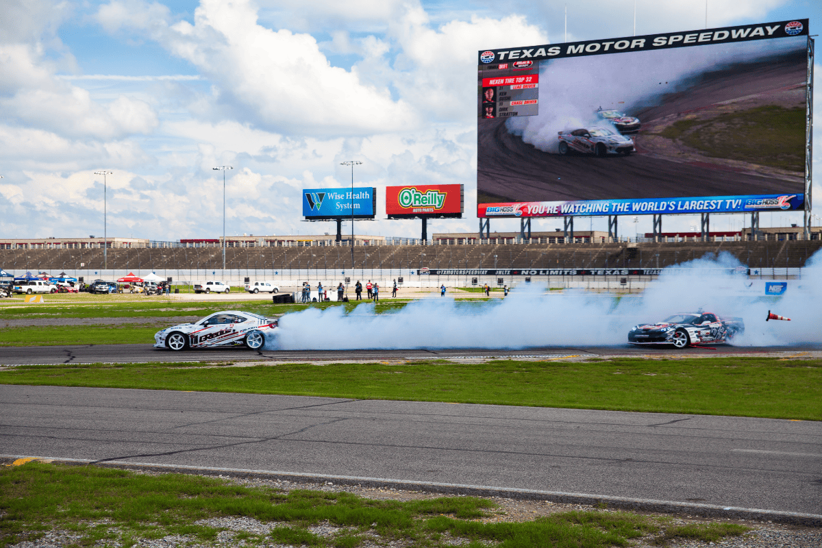 A dynamic race track scene showcasing a car and a truck racing side by side, highlighting their speed and power.