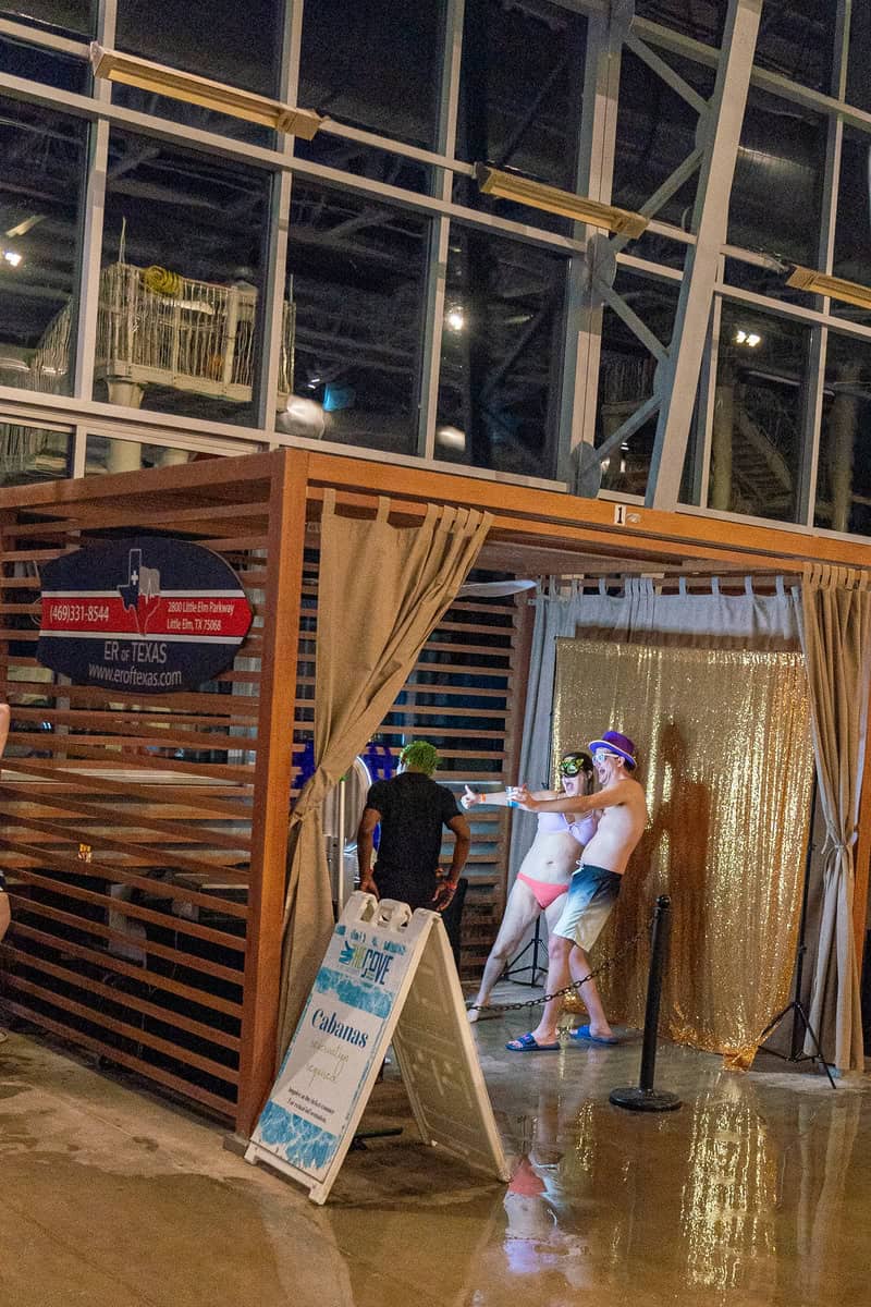 People in costume pose for photos at a cabana-themed party indoors.