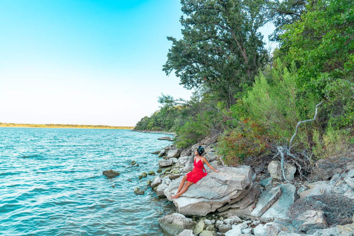 Person in red sitting on rocky lakeshore