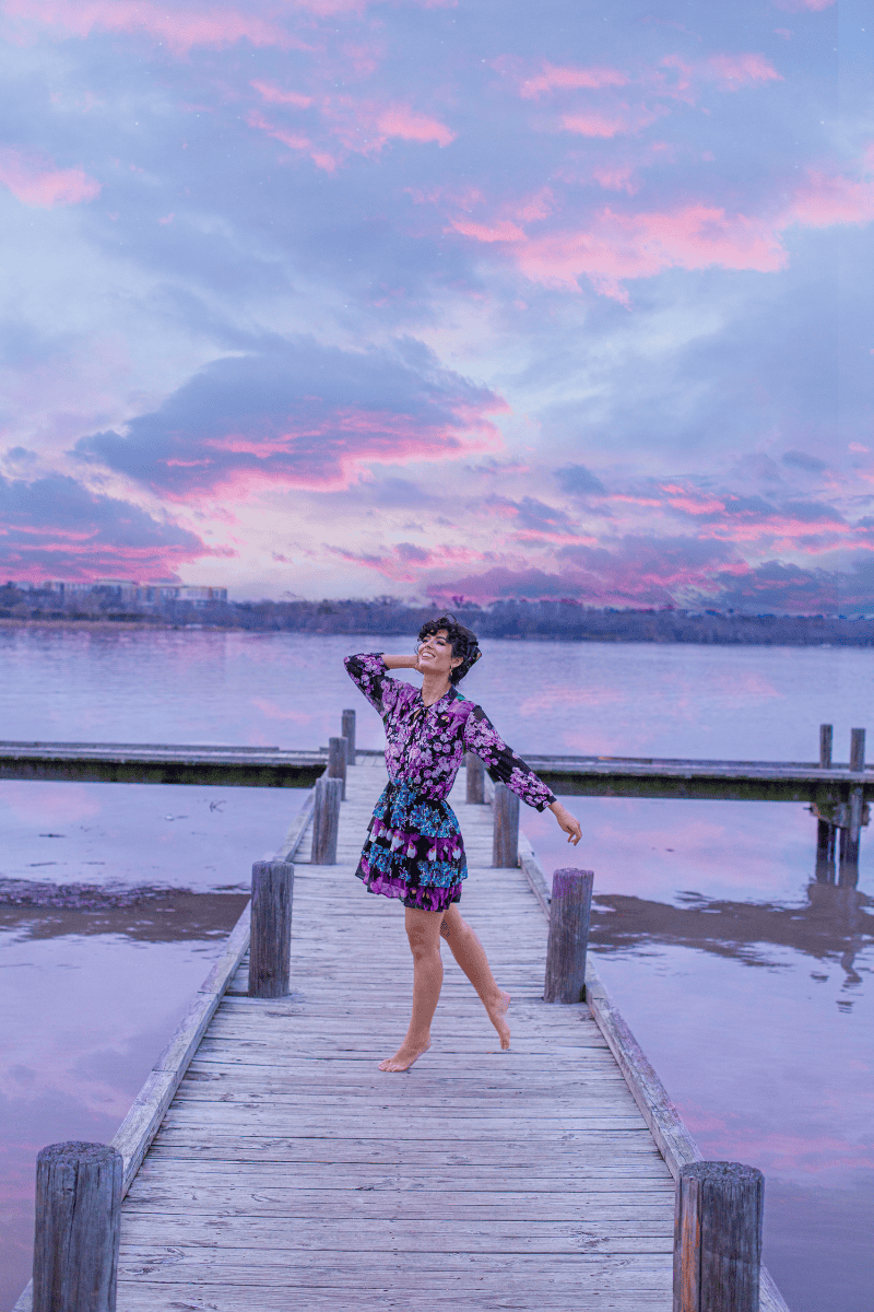 Person dancing on a dock at sunset