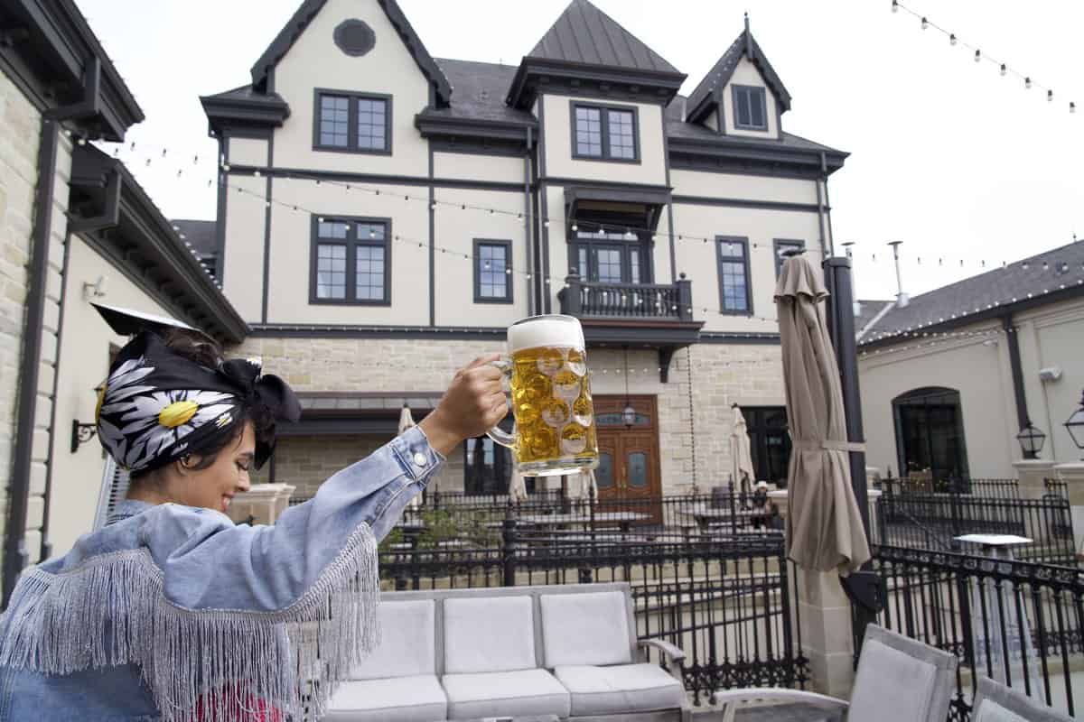 Person holding a large beer mug in front of an elegant house