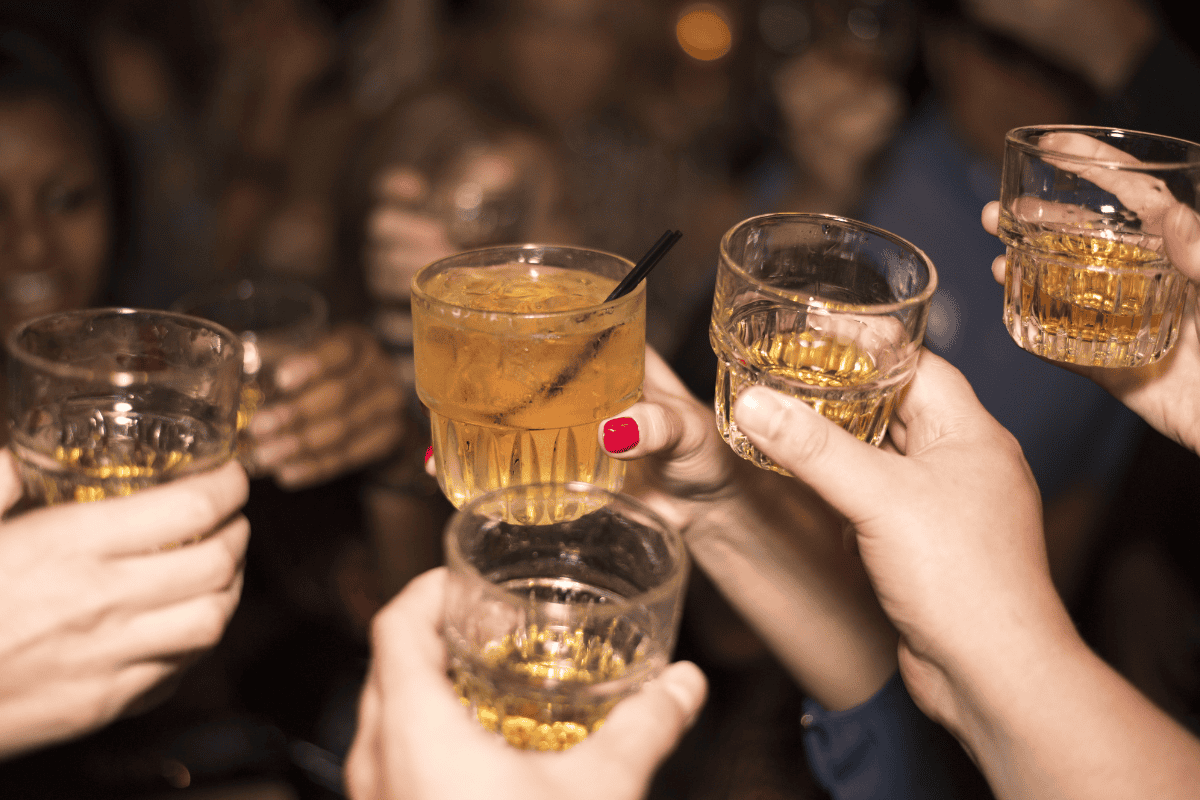 People toasting with various whiskey glasses.