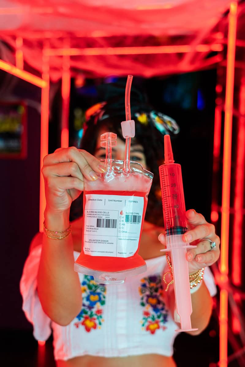 Person holding a blood bag and syringe novelty drink container