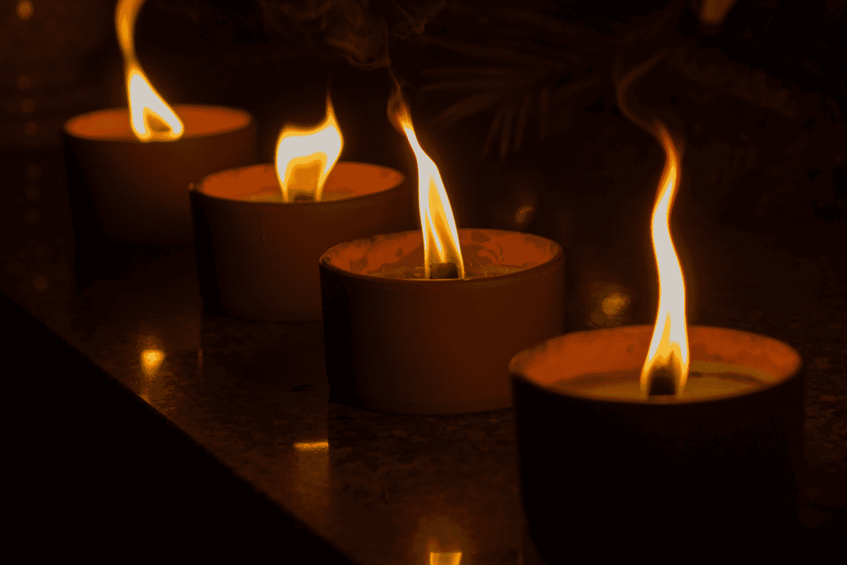 Three lit candles with tall flames in a dark setting.