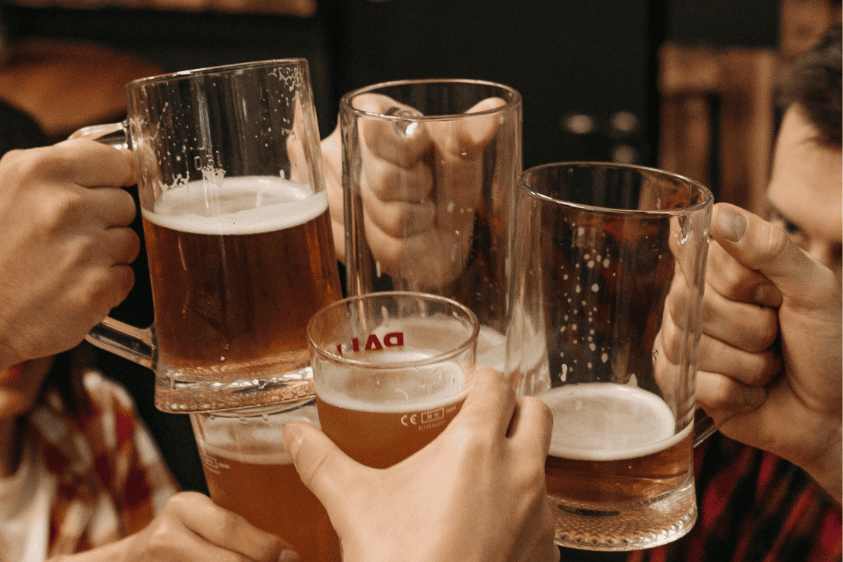 Group of people toasting with beer mugs and glasses.