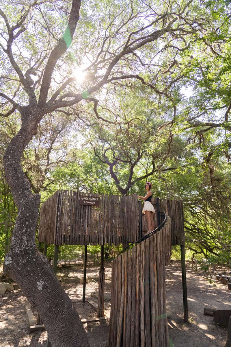 Person stands on a wooden lookout titled "Greenman's Lookout"