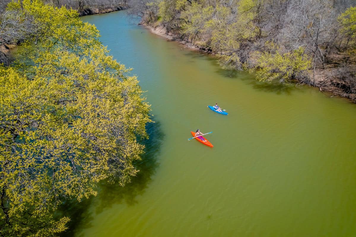 Two kayakers paddle peacefully down a river