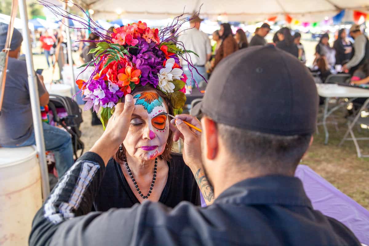 Person wearing a vibrant floral hat at an outdoor event.