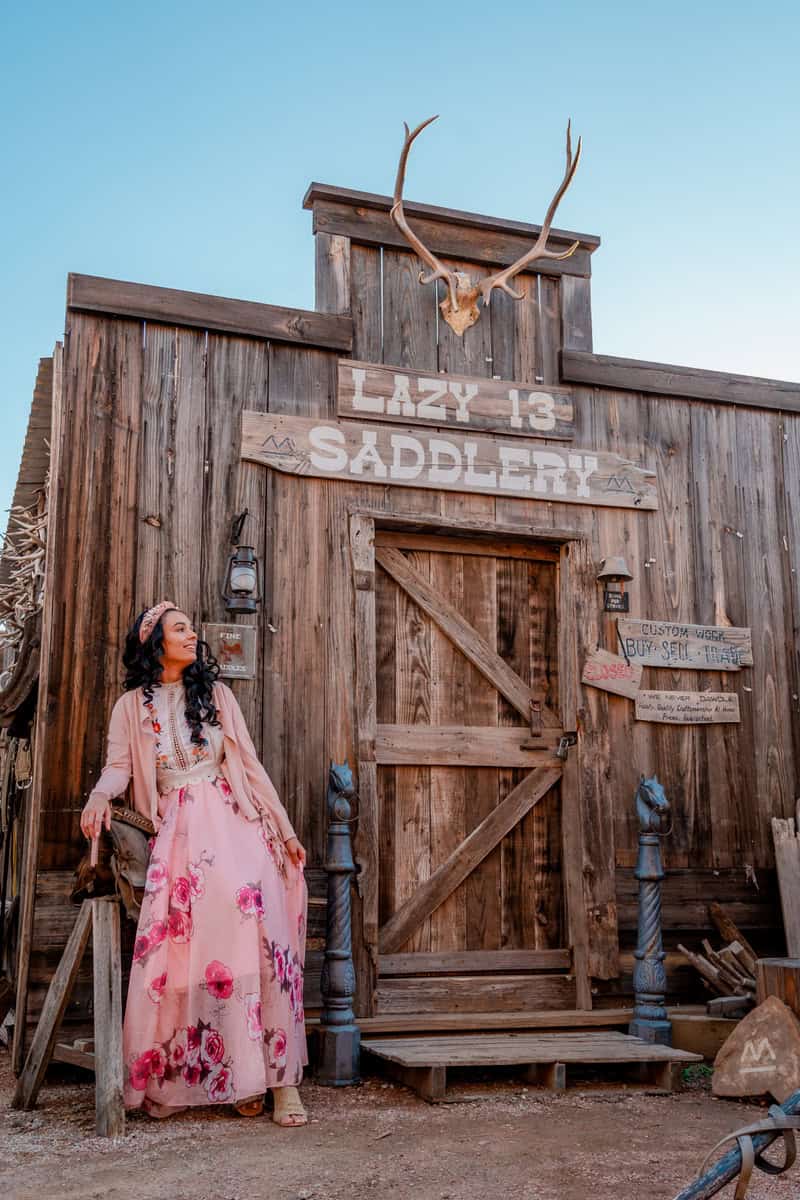  A woman in a pink dress poses in front of a wooden building