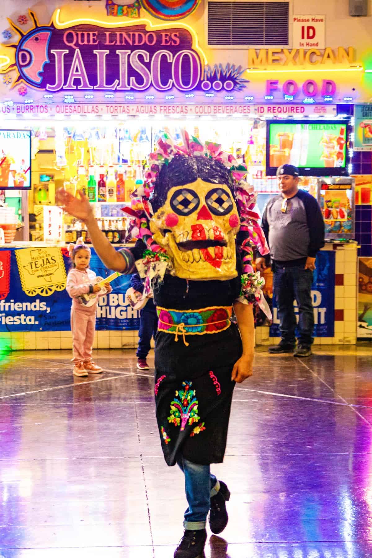 Person in traditional Mexican clothing in front of a food stall