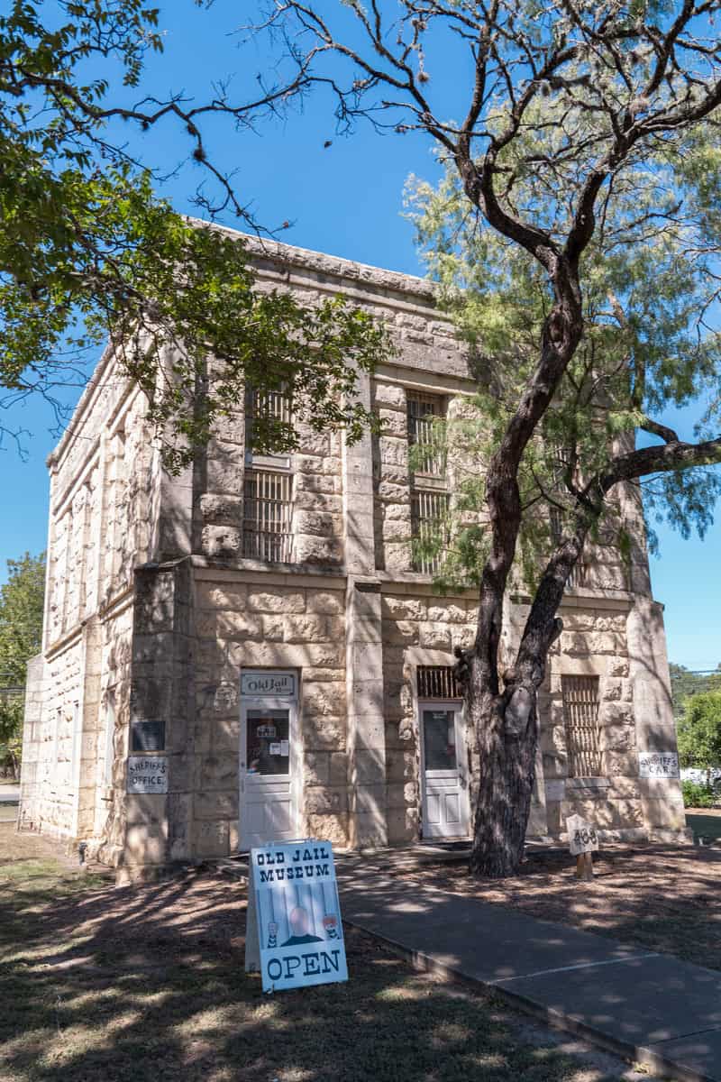 Stone building with barred windows labeled 'Old Jail Museum'