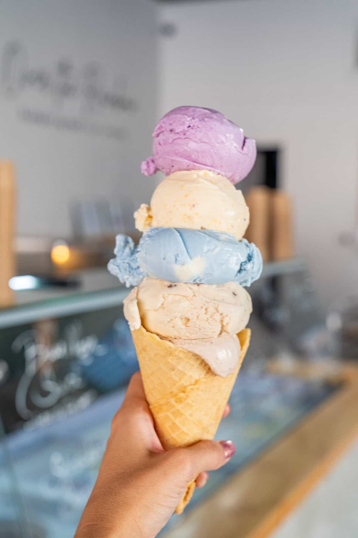 A person joyfully holds a colorful cone of ice cream