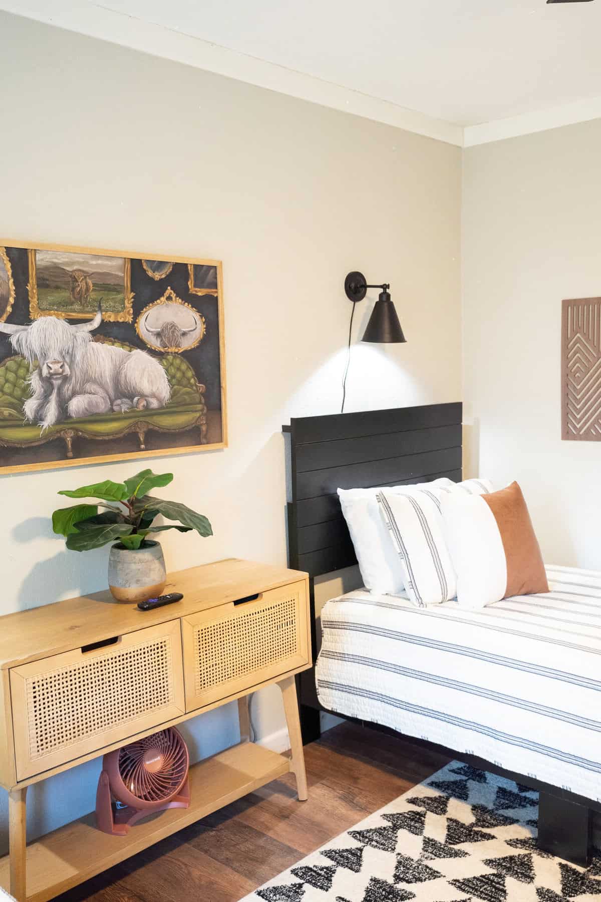 A cozy bedroom featuring a bed, a dresser, and a colorful painting 