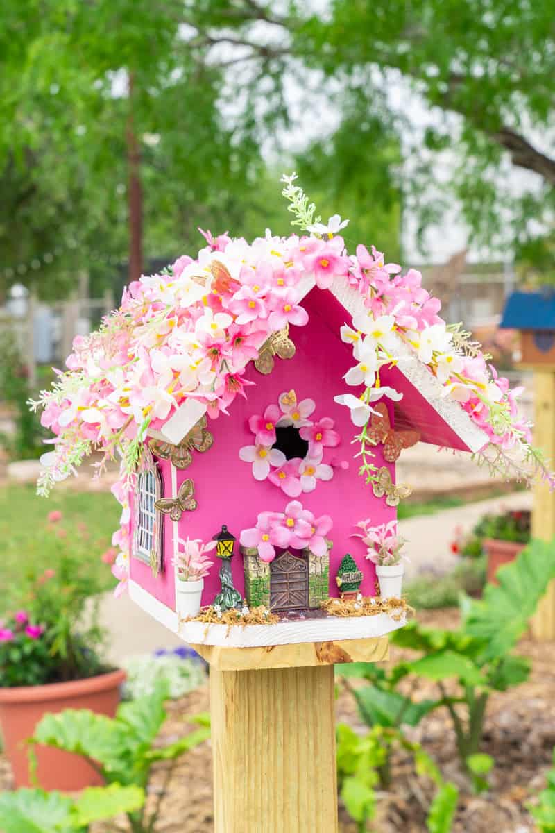 A lovely pink birdhouse featuring beautiful flowers