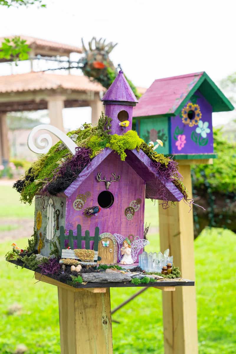 A lovely purple birdhouse featuring beautiful flowers