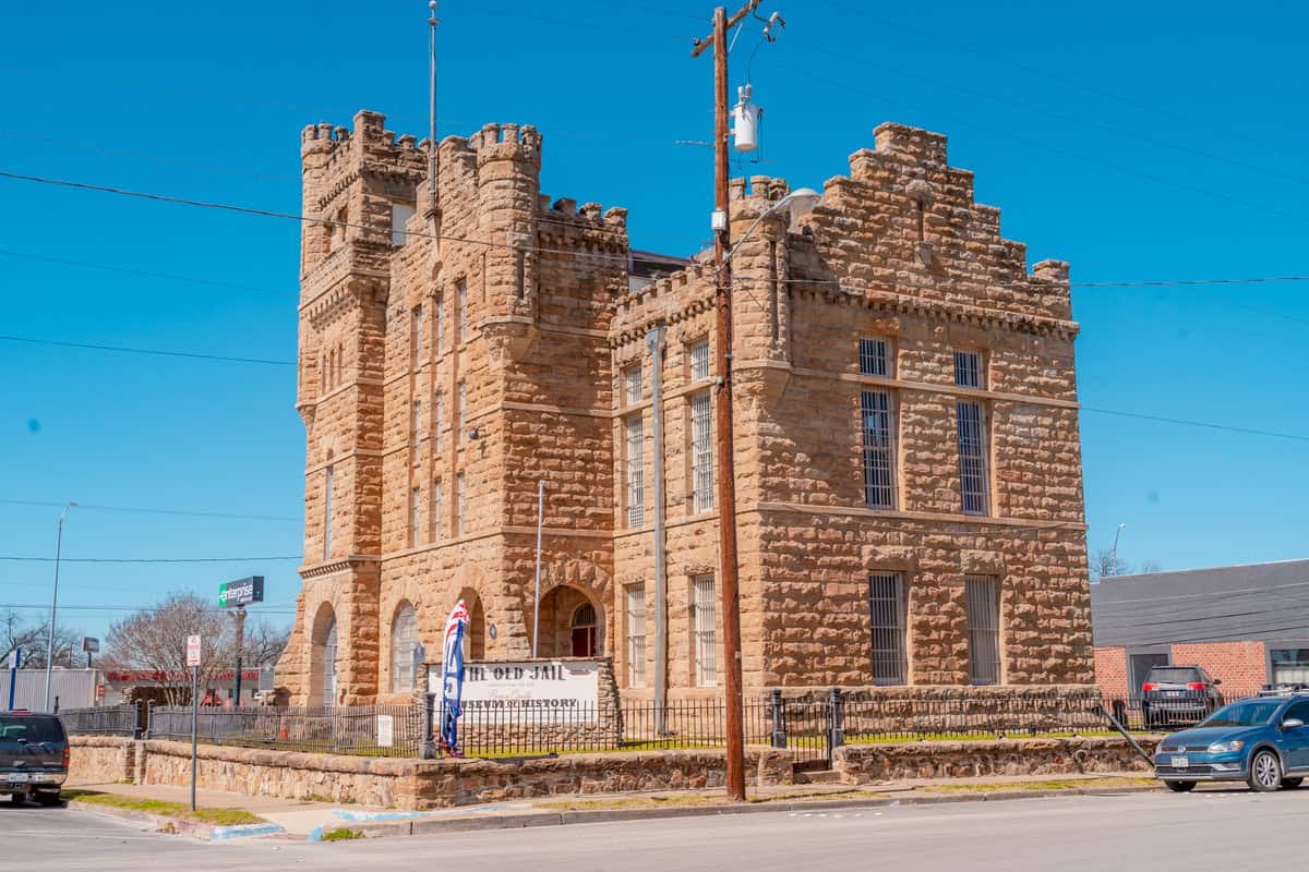 Stone castle-like building labeled "The Old Jail" with a clear blue sky.