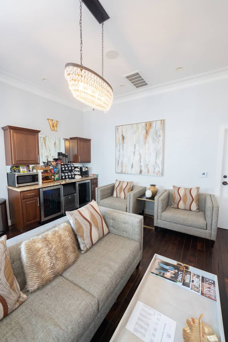 Elegant living room with a sofa, armchairs, kitchenette, and chandelier.