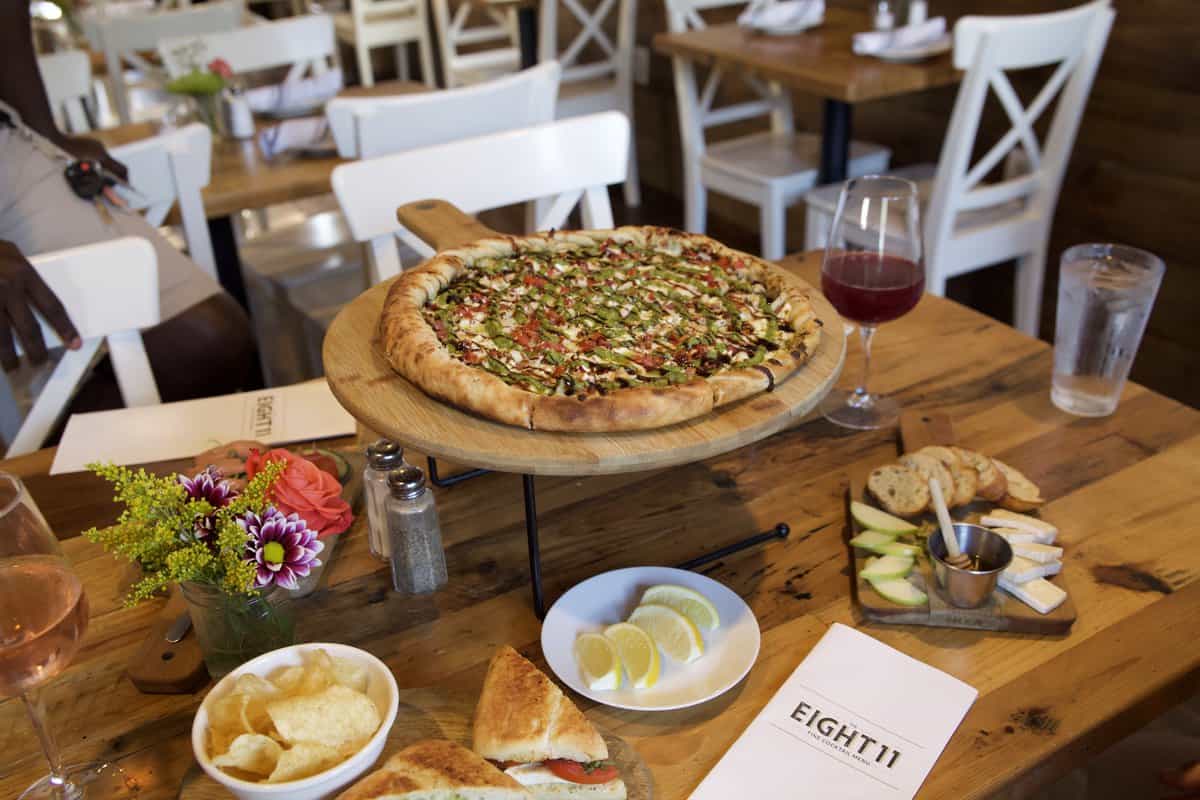 A rustic wooden table with pizza, wine, and appetizers