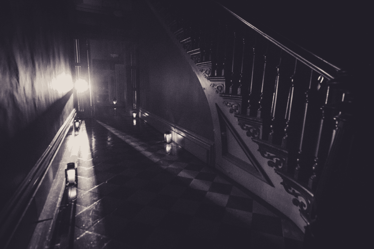 Dimly lit hallway with staircase and lanterns creating a moody ambiance.