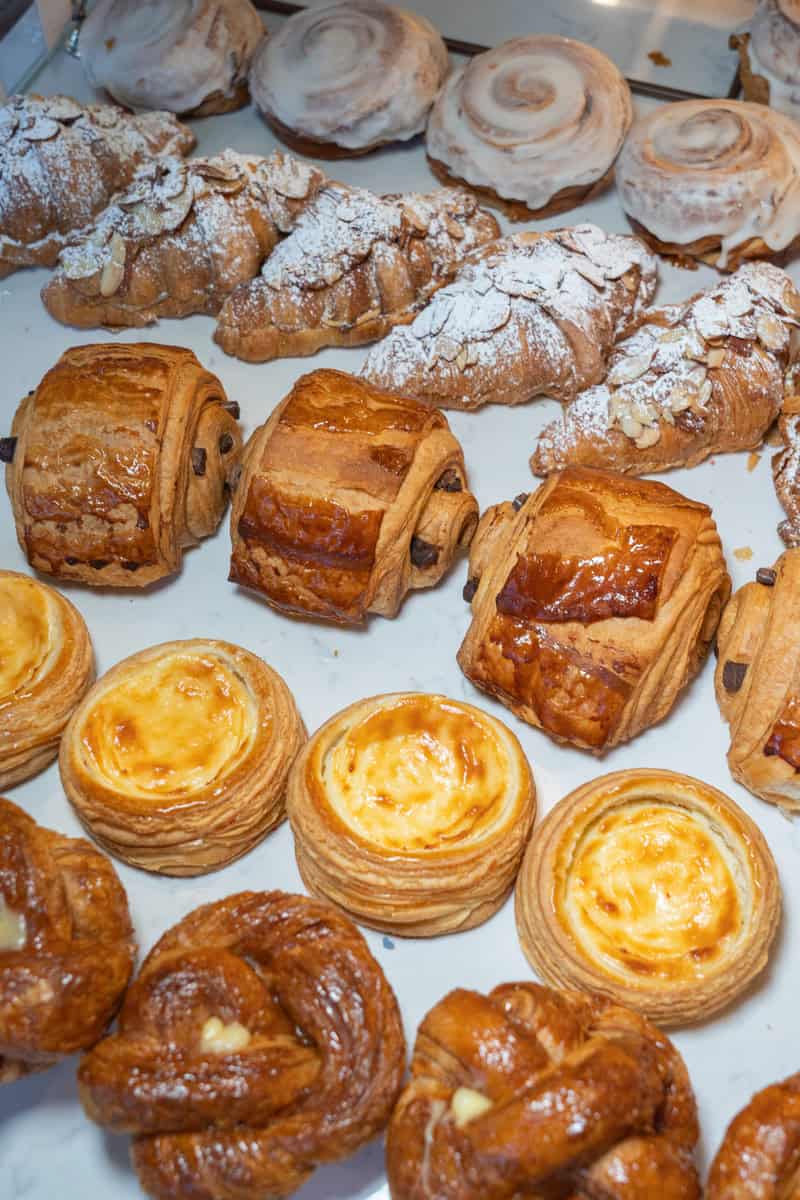 Assorted pastries including croissants, danishes, and custard tarts on a tray.