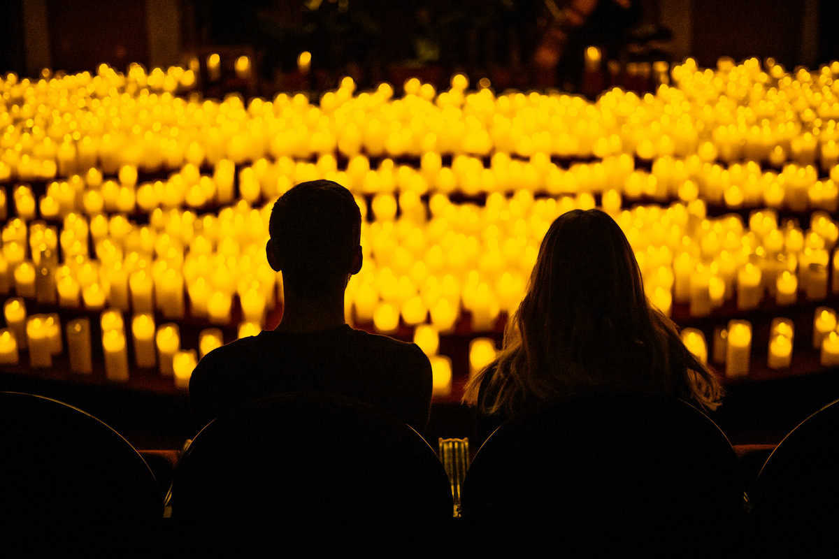 Two people silhouette against a backdrop of numerous glowing candles.