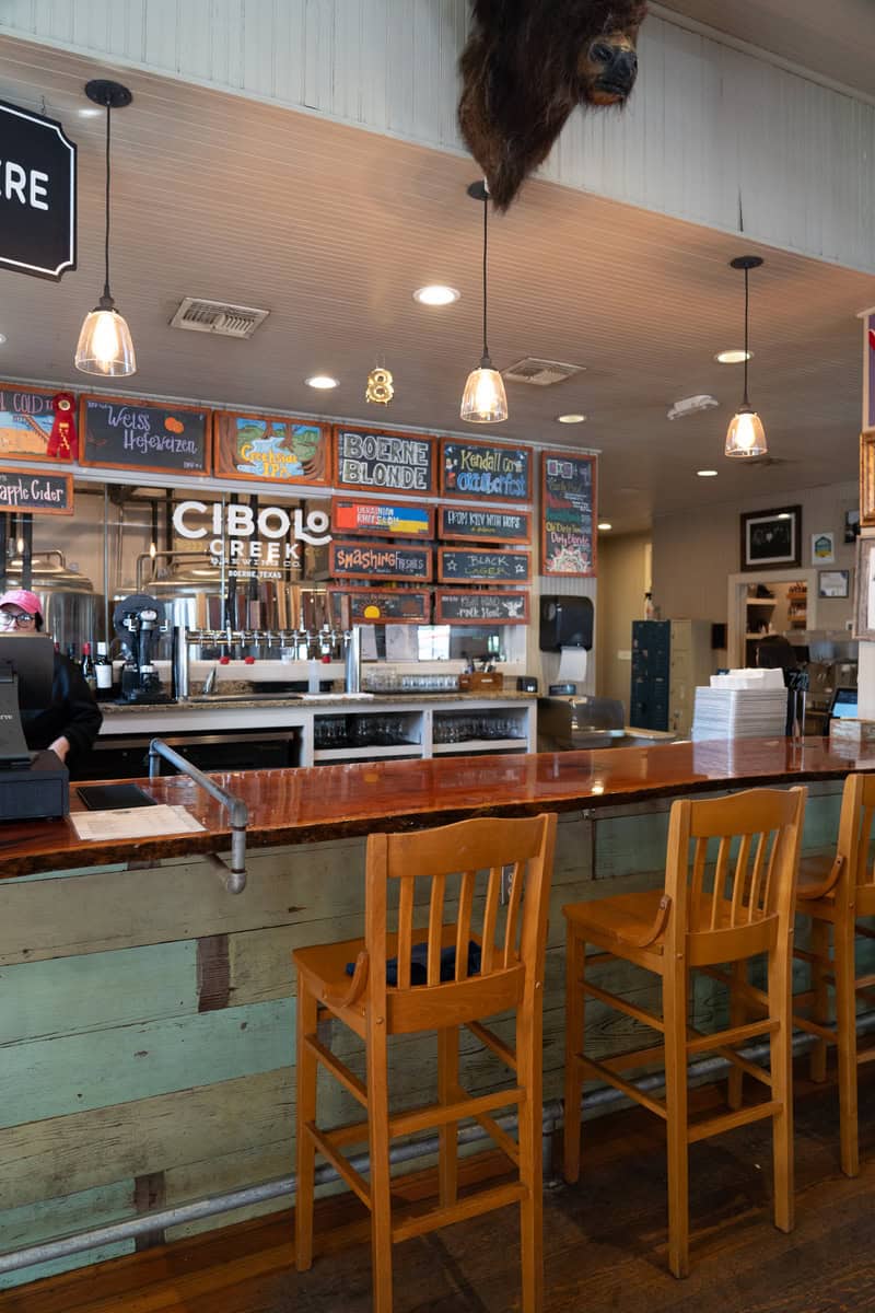 Interior of a rustic cafe with a wooden bar counter and hanging lights.