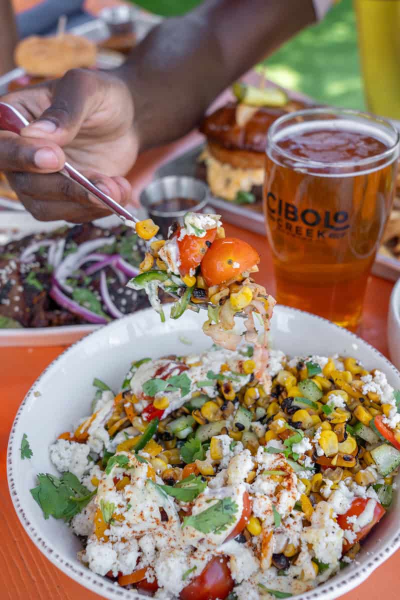 Person holding a forkful of a colorful salad