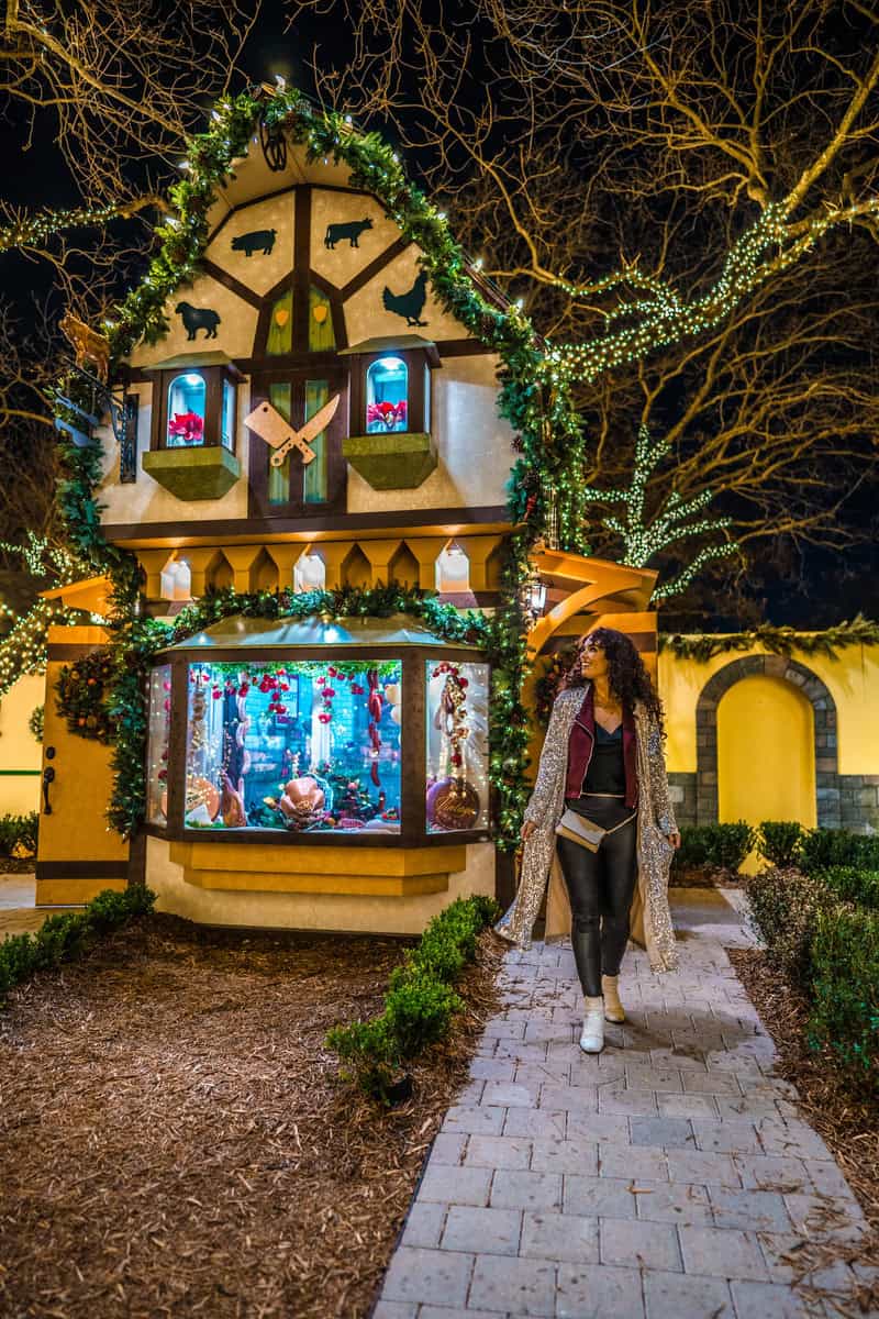 A person walking by a decorative, illuminated house façade