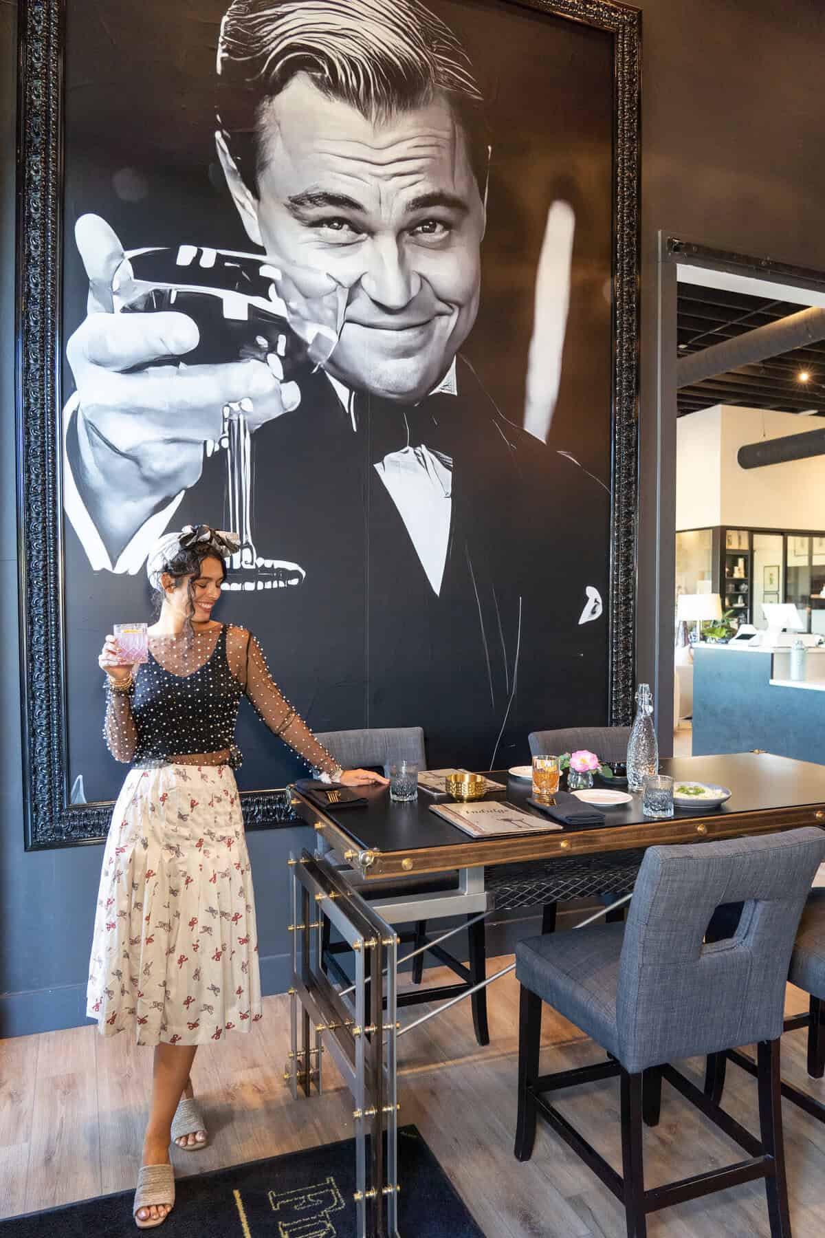 Woman in a polka dot top and floral skirt standing by a dining table