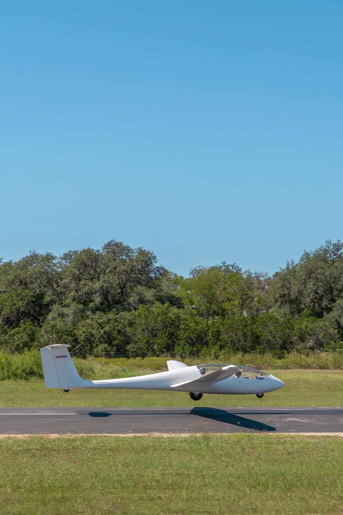 A white glider with long wings on a runway