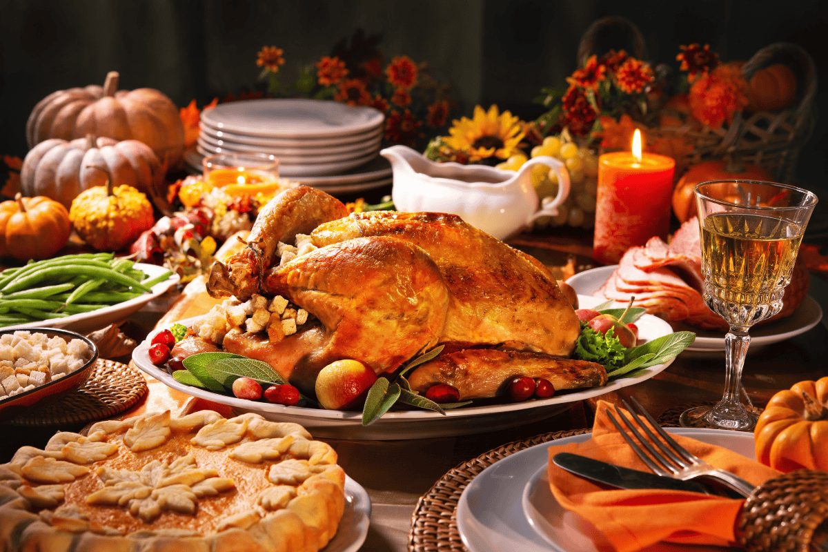 A Thanksgiving feast with roasted turkey, sides, pie, and candle decor.