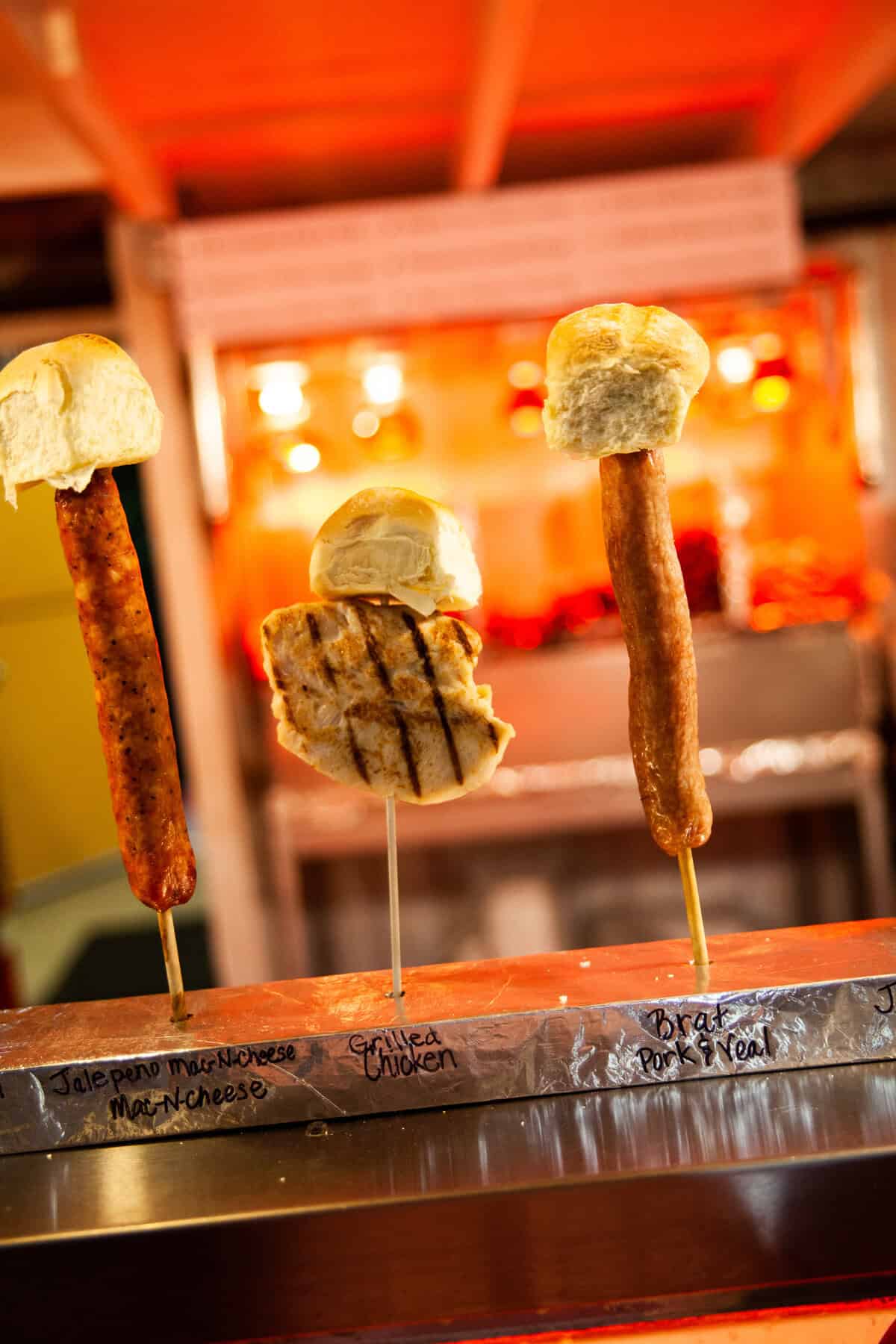 Three skewered sandwiches with meats and bread displayed on a warmer.