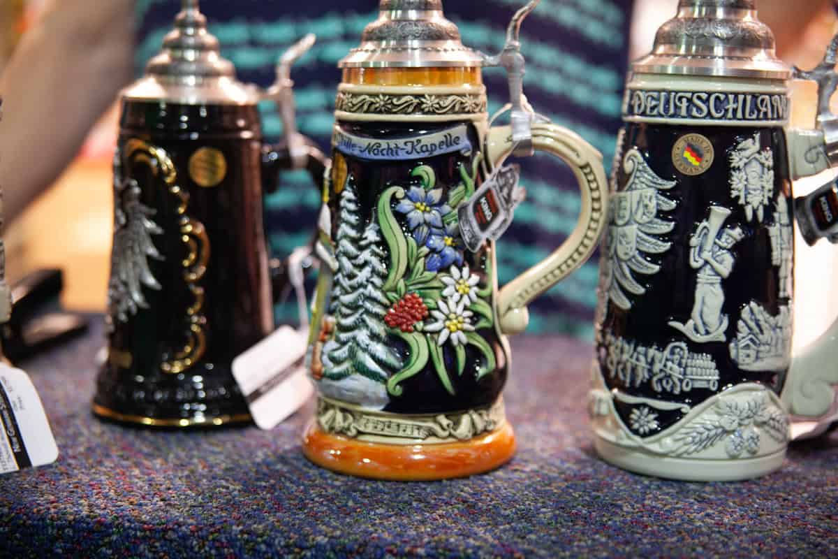 Two decorative German beer steins with intricate designs on a table.