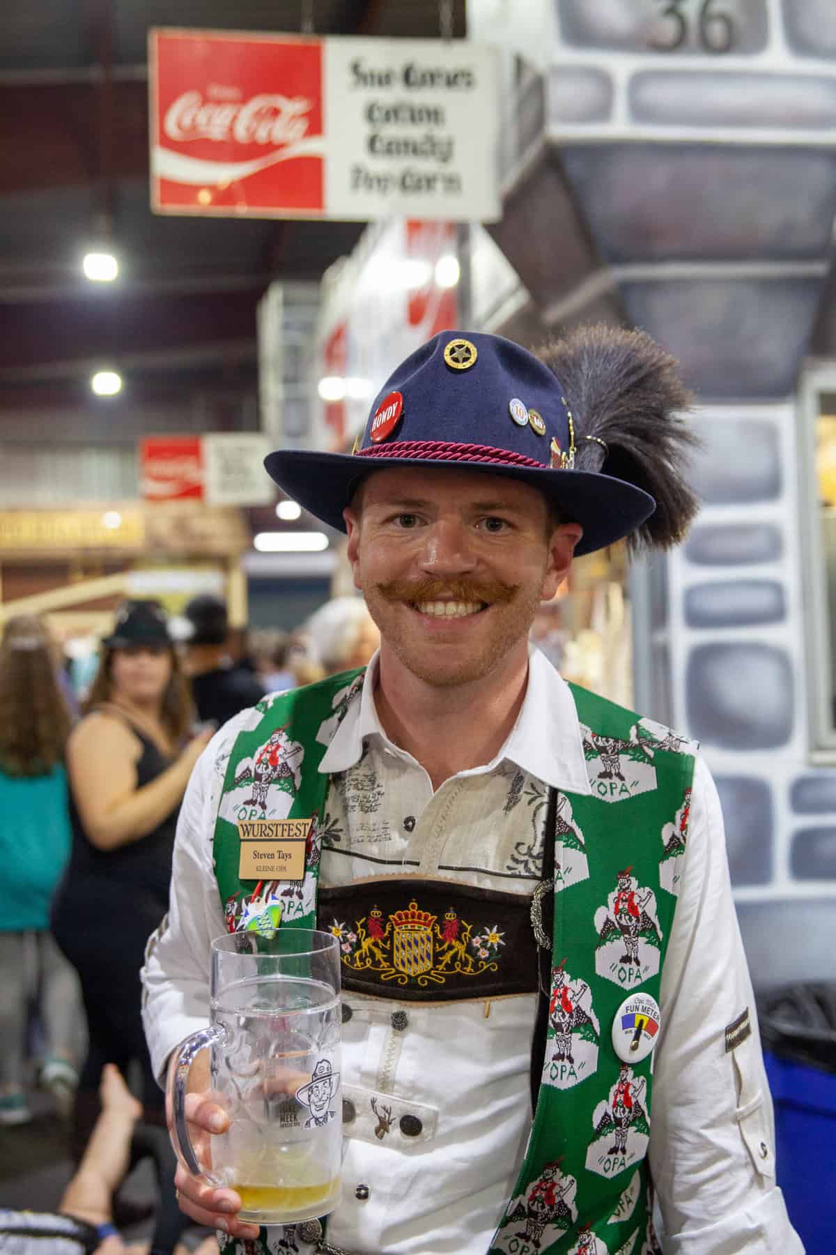 Person in traditional German attire holding a beer mug at a festival.