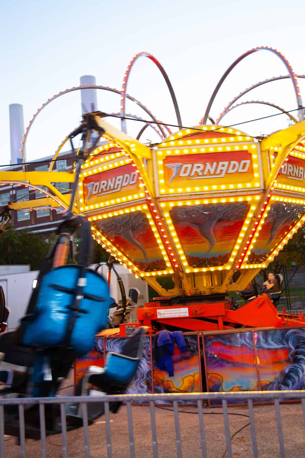 Amusement park ride "Tornado" with bright lights at twilight.