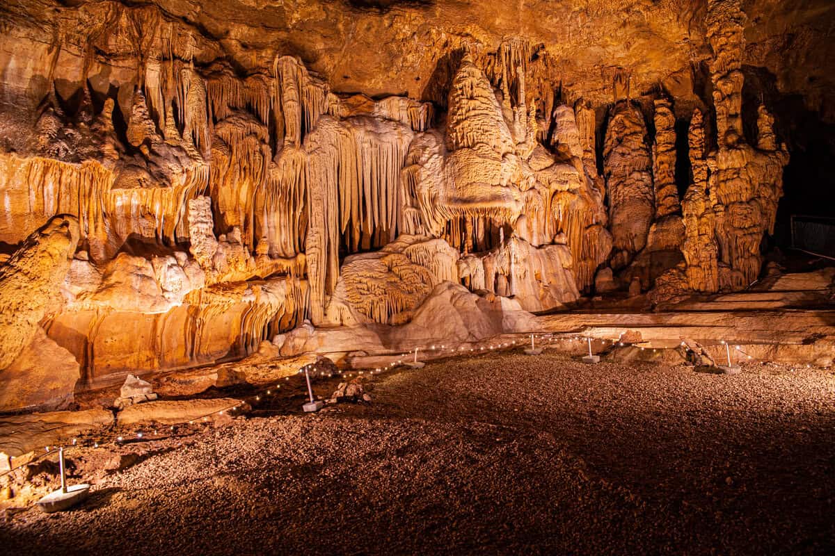 Illuminated stalactites and stalagmites inside a spacious cave.